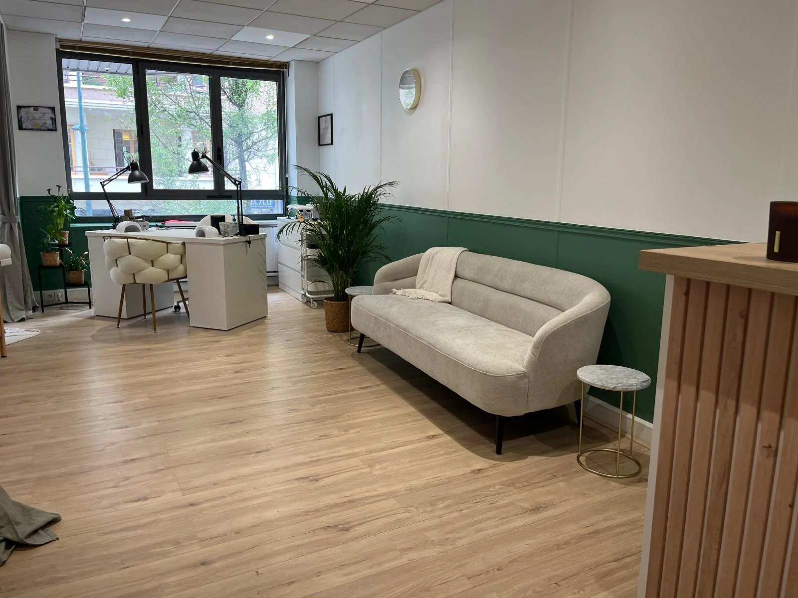 Le coin salon de l’institut, canapé clair et mur vert sapin